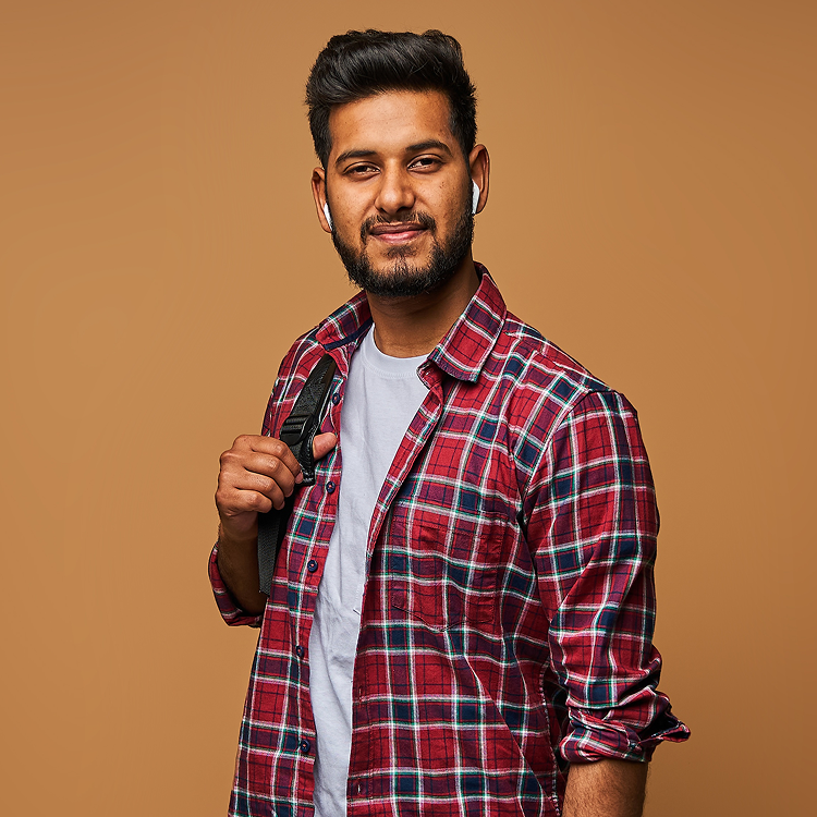 smiling-indian-man-casual-close-with-laptop-backpack-pastel-wall 1